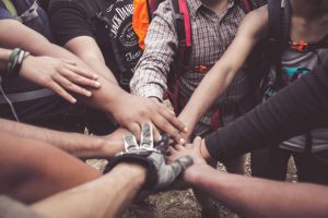 A team of people giving back put their hands together to cheer.