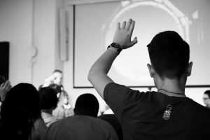 Student raising hand in class to provide feedback.